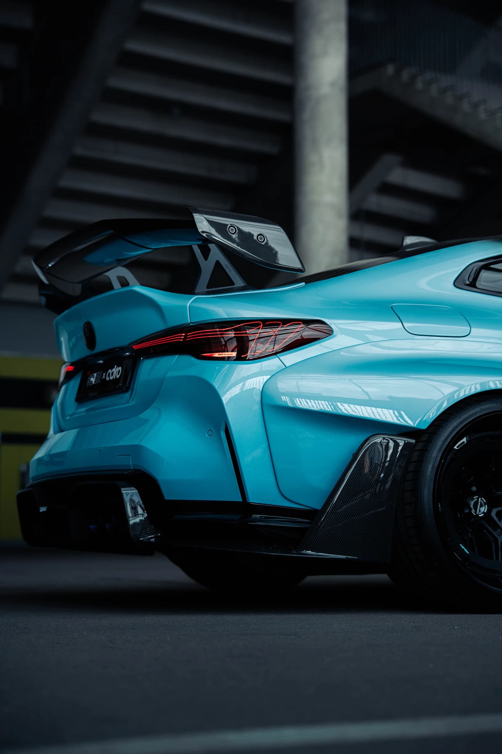 Turquoise performance car photographed beneath the arena structure at Ultrace 2025