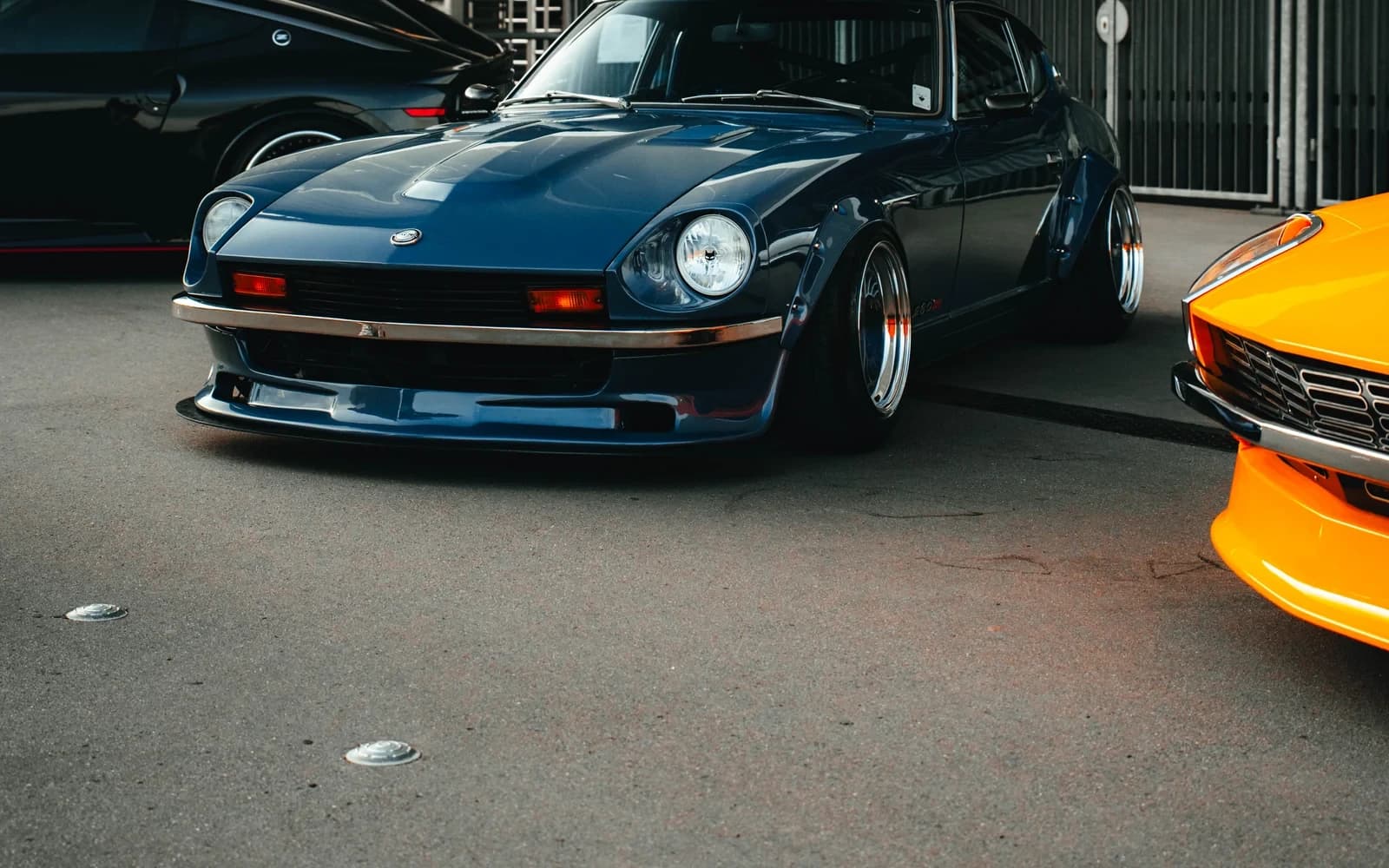 Dark blue classic sports car displayed between other builds at Ultrace 2025