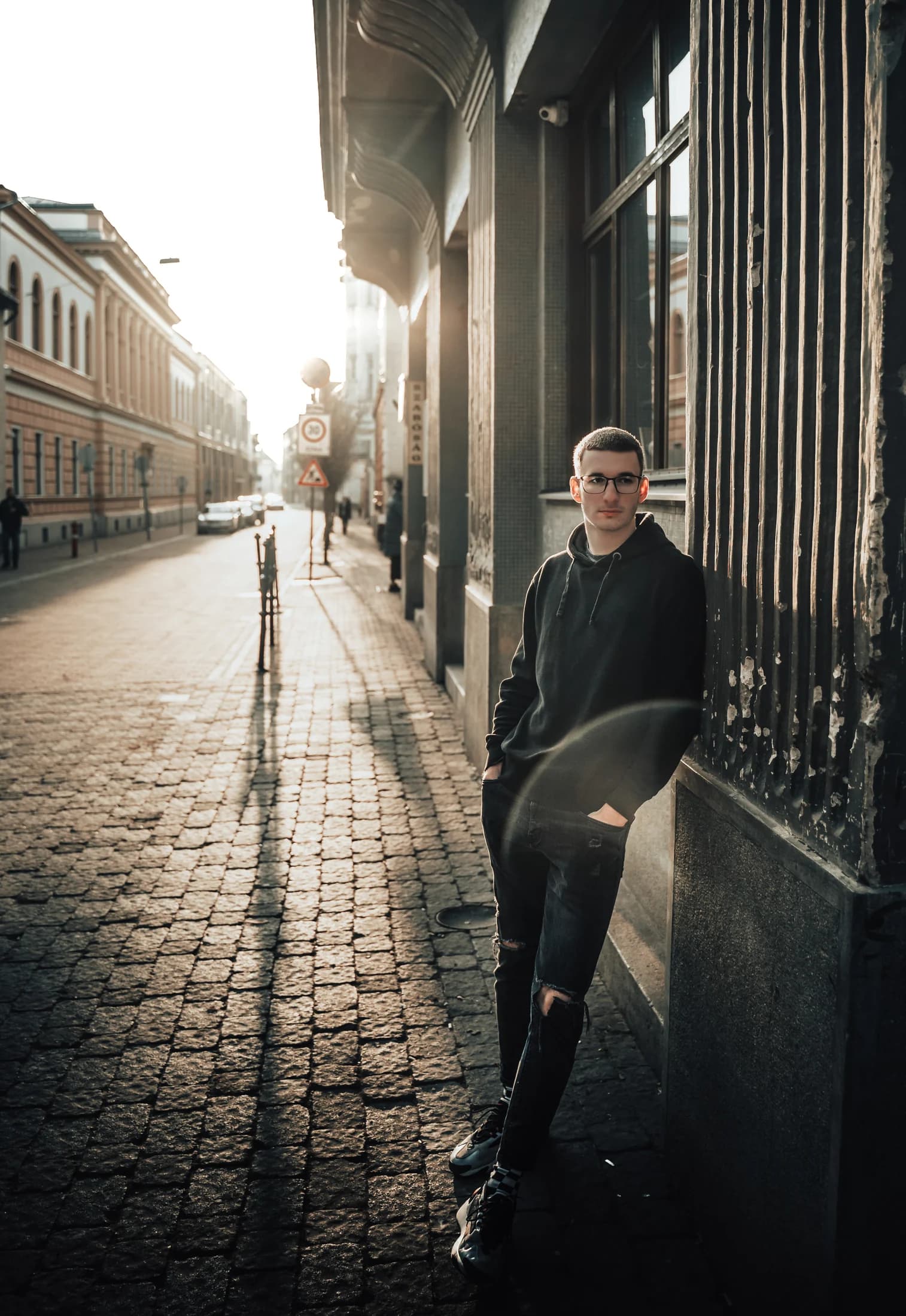Urban portrait of a man beside a sunlit building facade