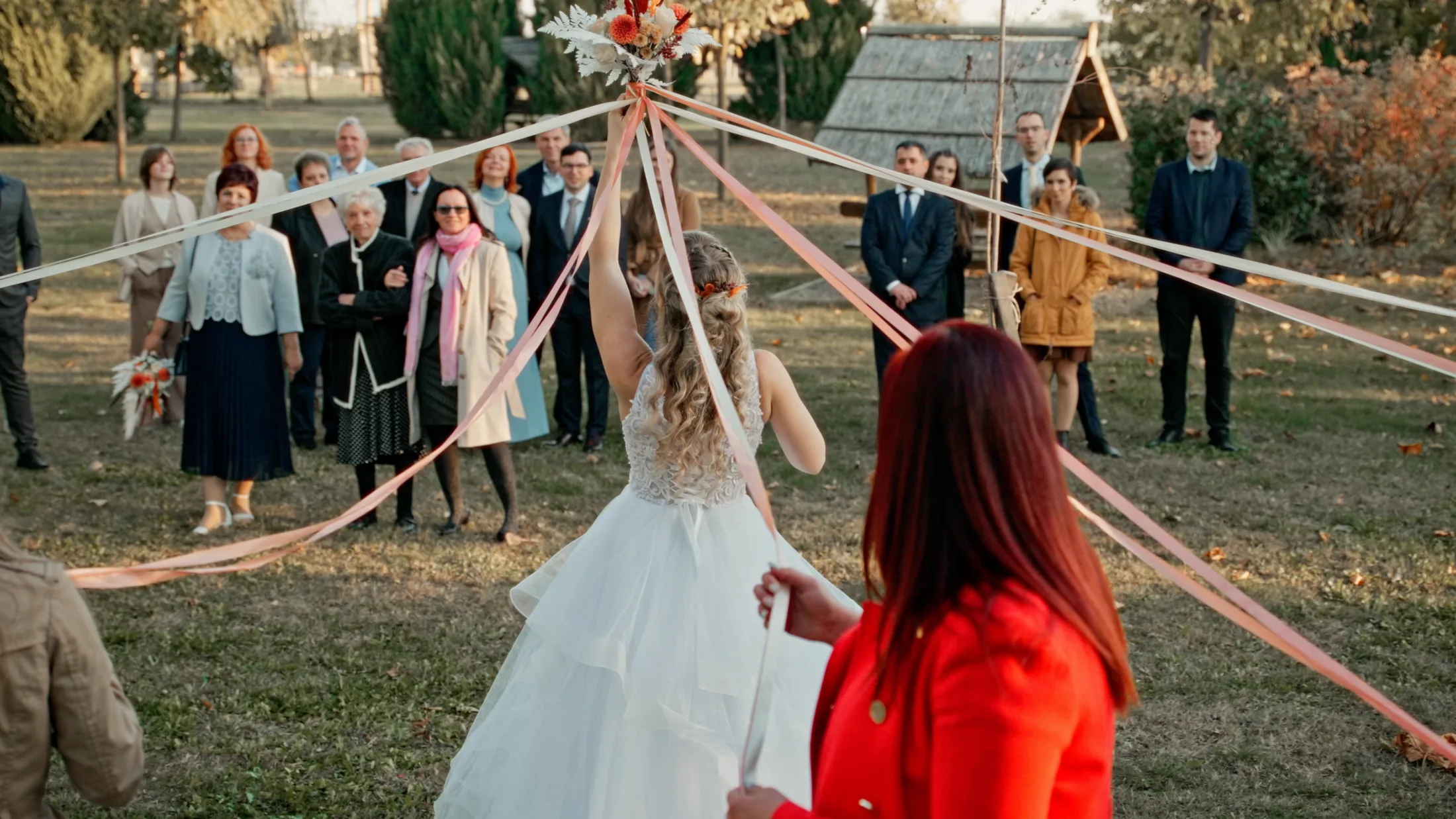Wedding guests gathered around Anó during an outdoor ribbon tradition