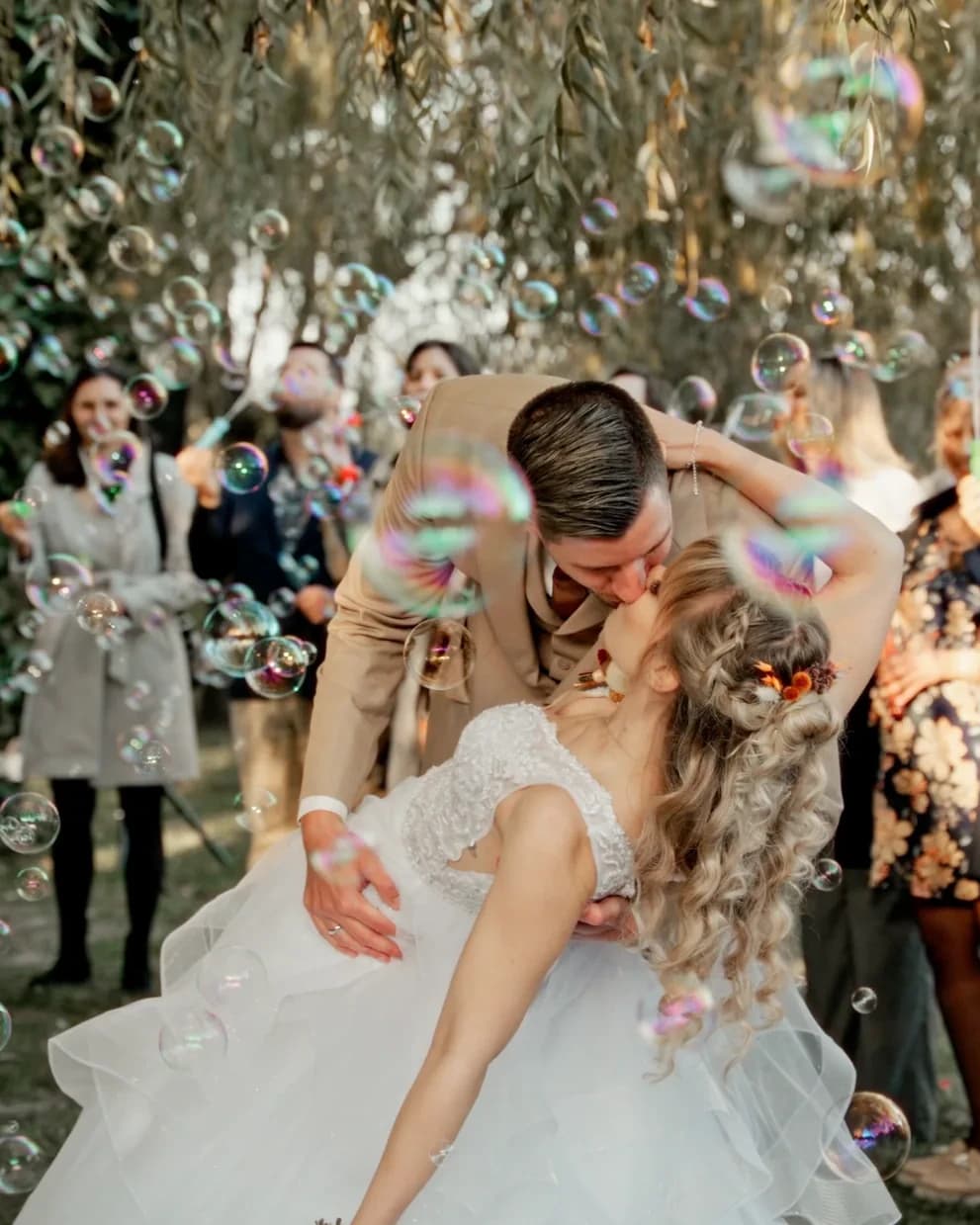 Anó and Bálint kissing among bubbles with their guests around them
