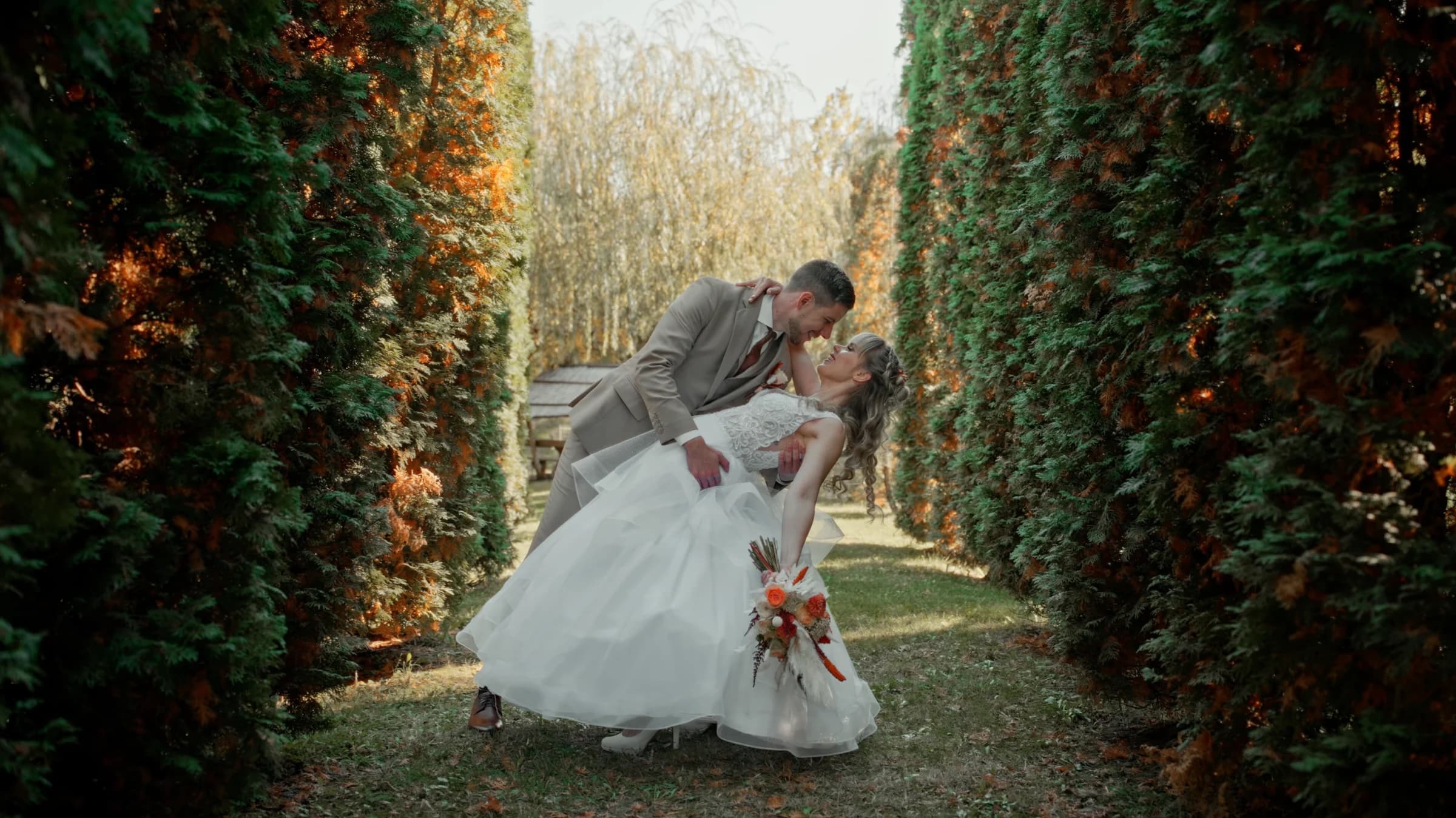 Anó and Bálint kissing between tall hedges at Nádas Pihenőpark