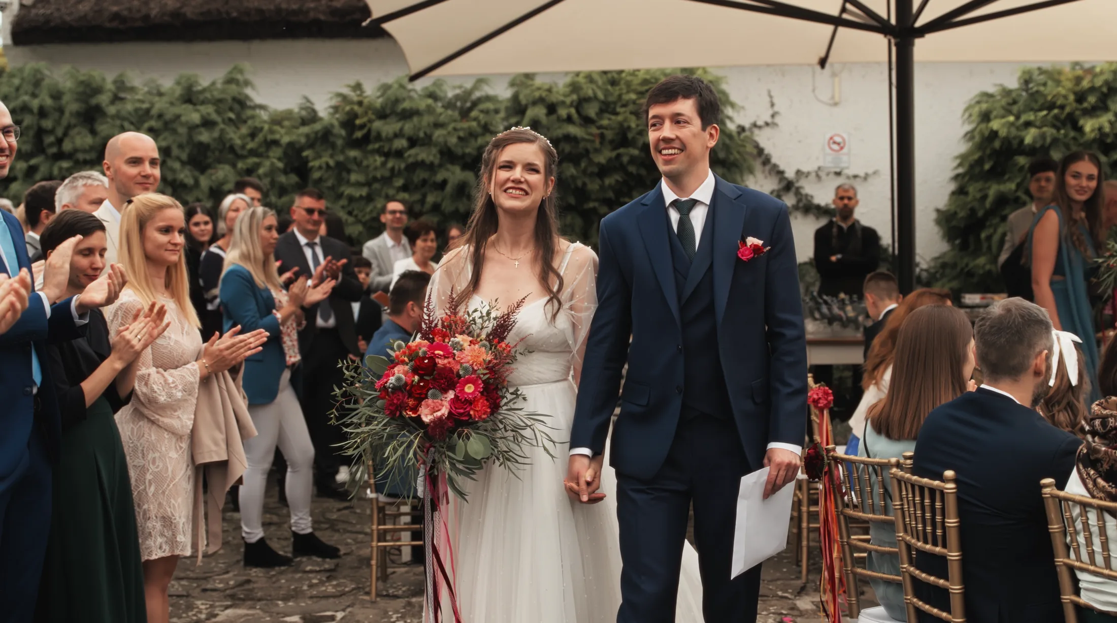 Dia and Beni walking back through their guests after the ceremony