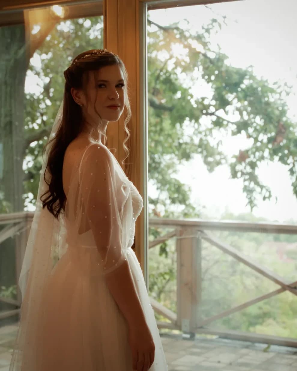 Dia standing by a window in her wedding dress before the ceremony
